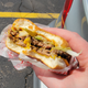 Hand holding double cheeseburger with bite taken out
